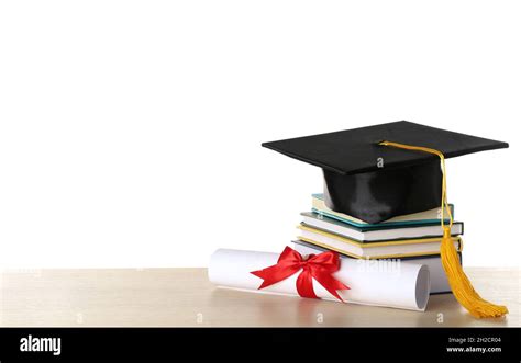 Graduation Hat With Books And Diploma On Table Against White Background