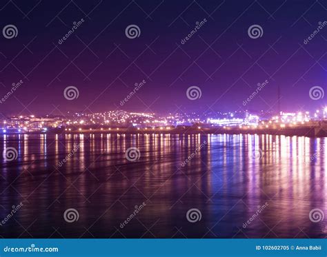 Panorama On Night Town With Reflection Of Colored Lights On The Water