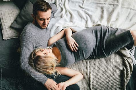 Pregnant Couple Cuddling On Bed By Stocksy Contributor Andrey Pavlov Stocksy