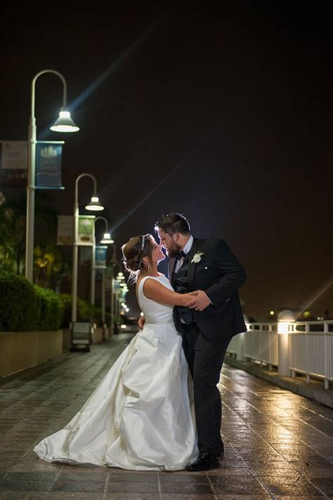 A Bride And Groom Kissing On The Sidewalk At Night Time With Street