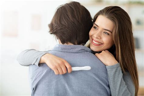 Closeup Of Happy Hugging Couple Holding Positive Pregnancy Test Stock