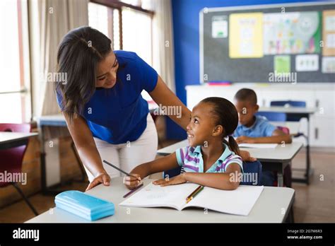 African American Female Teacher Teaching African American Girl In The Class At Elementary School