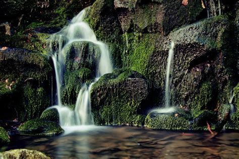 Little Waterfall In The Forest With Green Mossy Rocks And Clear