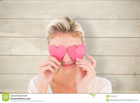 Composite Image Of Attractive Young Blonde Holding Hearts Over Eyes