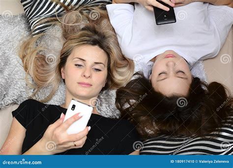 mom and daughter lie on the pillows and look at the screens of cell phones top view close up