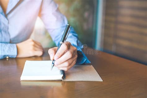 Woman Hand Is Writing On Notepad With Pen In Office Stock Image