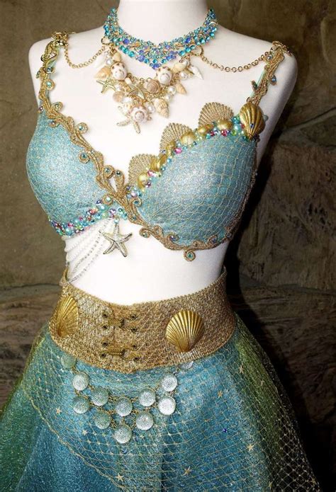 A Mannequin Wearing A Blue And Green Dress With Gold Jewelry On Its Chest