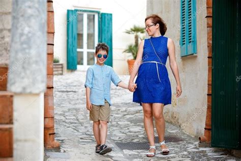 Young Mother And Her Son Walking Outdoors In City Stock Photo