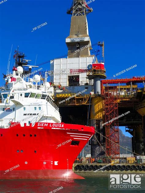 An Oil Rig In Harbour For Maintenance With Its Towing Tug Moored