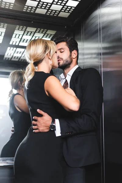 sensual pareja desnudándose mientras se besa en oficina ascensor — beso adultos jóvenes stock