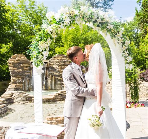 First Kiss Of Newly Married Couple Under Wedding Arch Stock Image