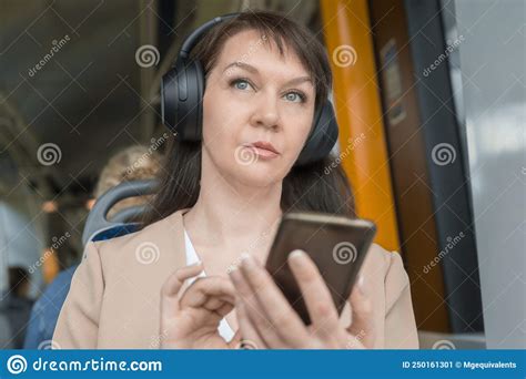 Portrait Of A Woman Sitting In A Bus And Listening To Music In Wireless Headphones During A Trip