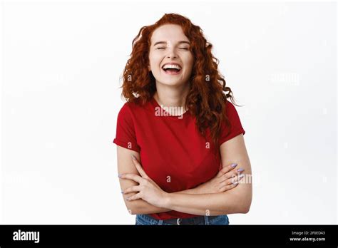happy redhead girl with curly hair laughing positive with eyes closed cross arms on chest and