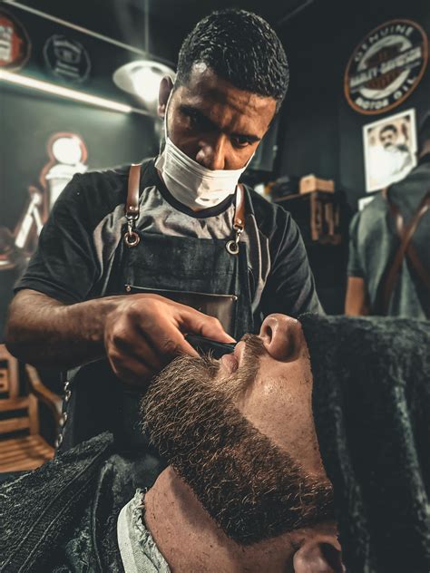 A Barber Grooming A Mans Beard · Free Stock Photo