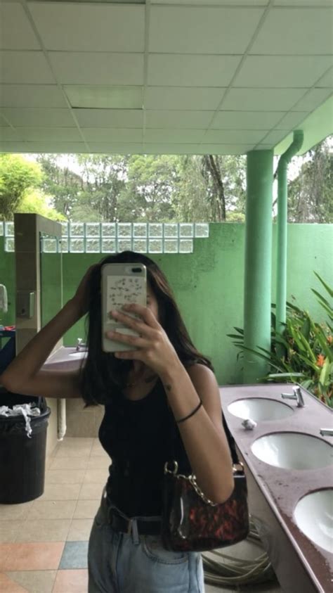 A Woman Taking A Selfie In A Public Restroom With Sinks And Mirrors