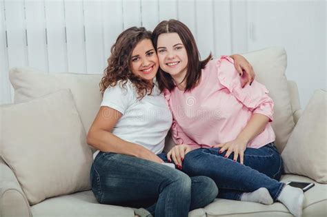 Two Amazing Girls Sitting On The Different Sides Of The Sofa Talking