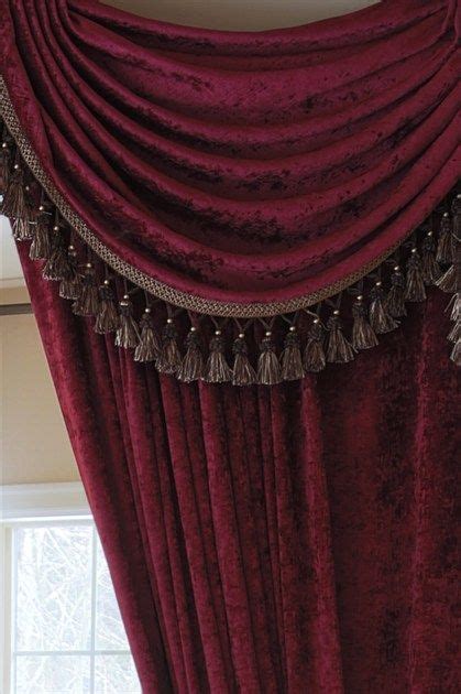 A Red Curtain With Tassels Hanging From Its Sides In Front Of A Window