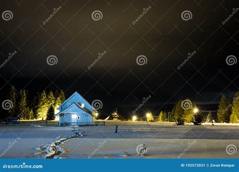 Traces In The Snow Leading To Small House House Isolated At Night In