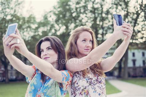 Two Young Female Friends Taking Selfie On Smartphones Side By Side — Communication Trees