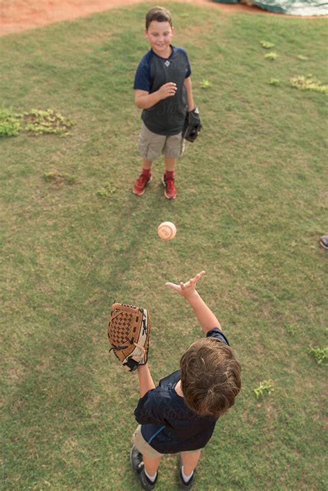 Two Brothers Play Catch On A Baseball Field Del Colaborador De