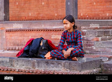 A Local Dark Haired Hindu Young Girl With An Orange Tilaka Mark On Her Forehead Sits Cross