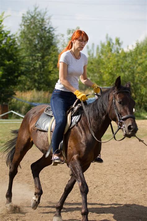 A Redhead Woman Riding A Horse On A Farm Forest On The Background