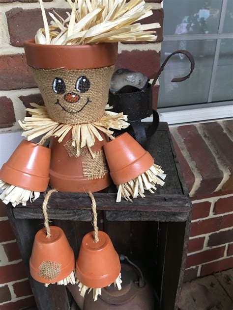 A Scarecrow Made Out Of Clay Sitting On Top Of A Shelf Next To Boots