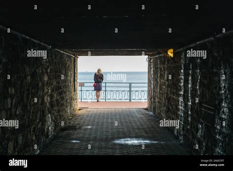 Lonely Woman Stand At The End Of A Tunnel Looking At The Sea Stock