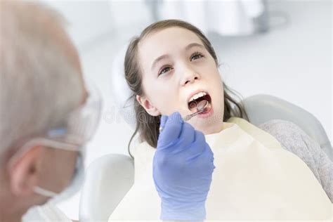 Dentist Examining Patient With Open Mouth At Dental Clinic Stock Photo