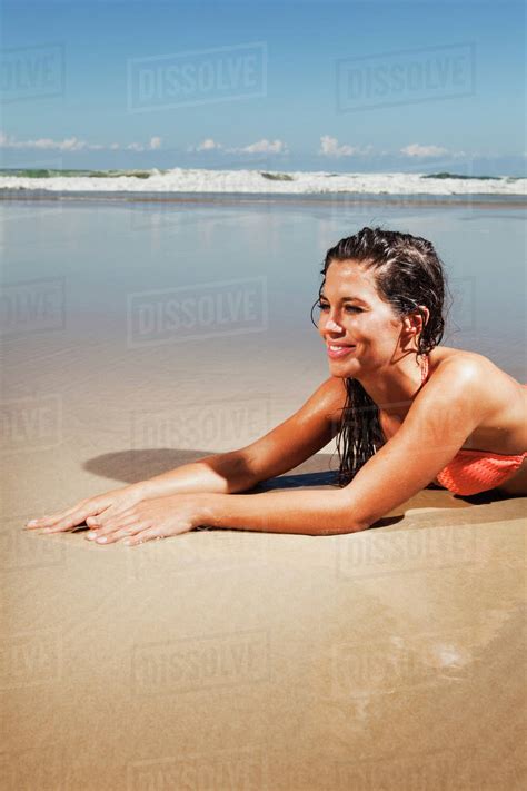 A Woman In A Bikini Lays On The Sand Of A Beach At Low Tide Gold Coast