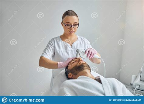 Female Cosmetologist Treating Male Skin With Laser Device Stock Image