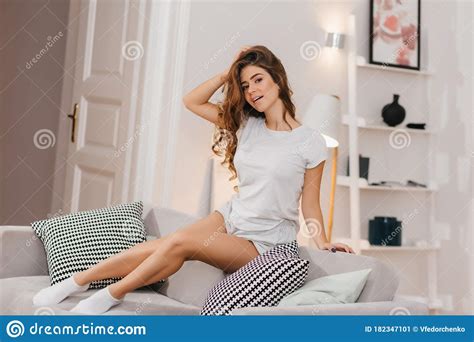 sensual woman in white socks posing on sofa and touching her long hair indoor portrait of