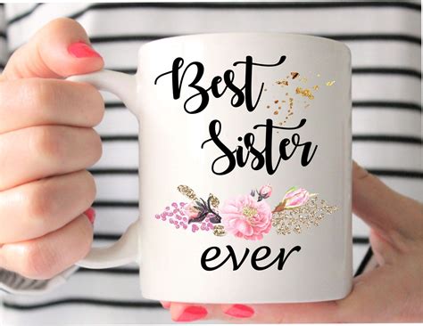 A Woman Holding A White Coffee Mug With The Words Best Sister Ever On