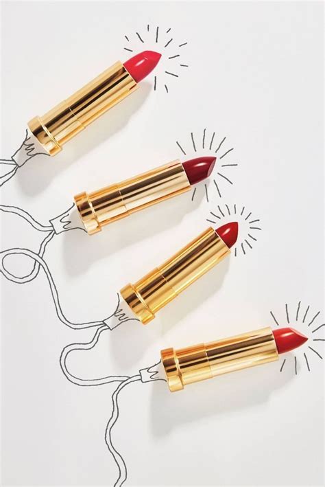 Three Red And Gold Lipsticks On Top Of Each Other In Front Of A White