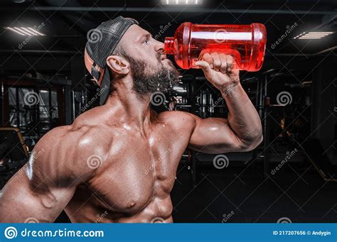 Muscular Man In The Gym Drinks From A Huge Bottle Fitness And