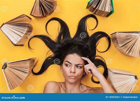 Serious Young Woman Lies Isolated On Yellow Background Over Books Stock