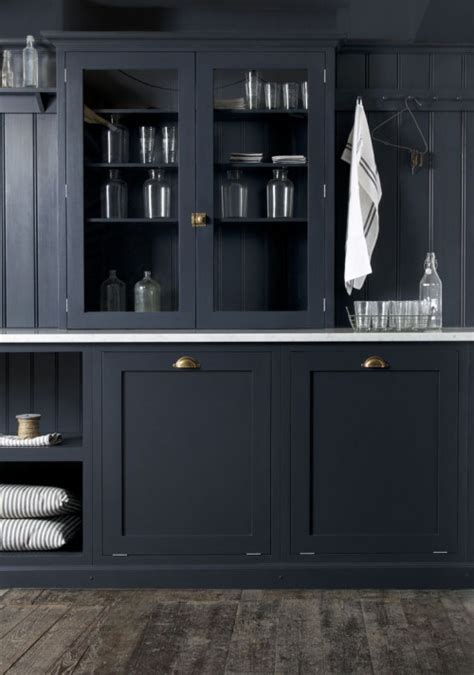 Stunning kitchen features navy blue vanity cabinets adorned with aged brass hardware fitted with side by side glass front wine coolers finished with black glass doors topped with navy blue kitchen wet bar, fitted with shaker cabinets painted benjamin moore hale navy and accented with brass pulls. On the cusp of a kitchen | My Friend's House