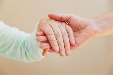 Close Up Of Senior Woman And Young Woman Holding Hands Care And