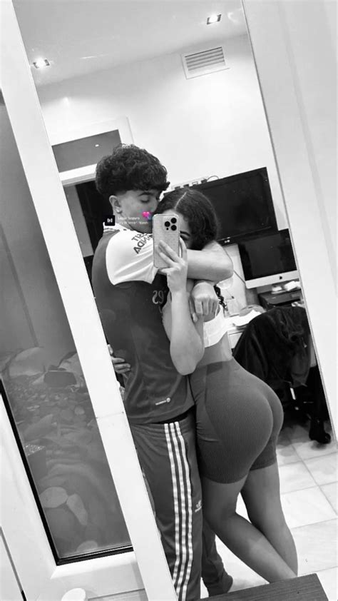 A Man And Woman Standing In Front Of A Mirror Taking A Selfie With Their Cell Phone