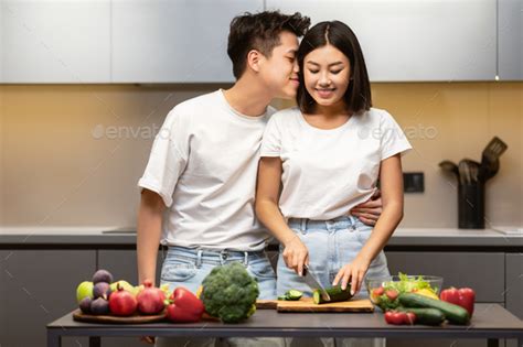 Loving Japanese Husband Kissing Wife Preparing Dinner Together In Kitchen Stock Photo By