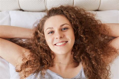 Top View Of Cheerful Young Female With Curly Bushy Hair Has Plea Stock