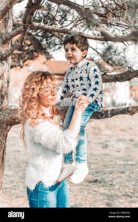 Mom Holding Her Toddler Son While He Is Sitting On A Tree Love And