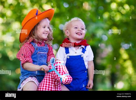 Little Boy And Girl Dressed Up As Cowboy And Cowgirl Playing With Toy
