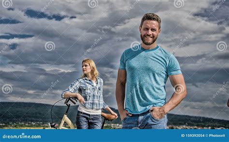 man bearded macho posing confidently in front of shy girl with bike cycling instructor concept