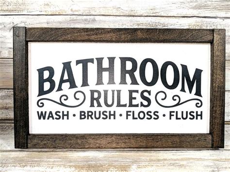 The Bathroom Rules Sign Is Mounted In A Wooden Frame
