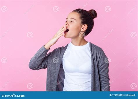Portrait Of Sleepy Brunette Teen Girl Yawning And Covering Mouth With
