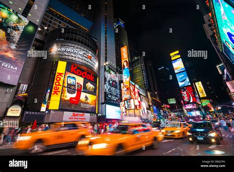 Traffic In Times Square At Night With Taxi Cabs Driving Through The