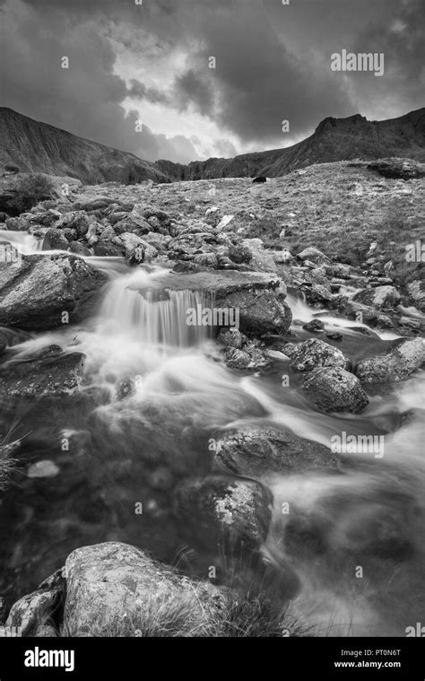 Black And White Landscape Image Of River Flowing Down Mountain Range