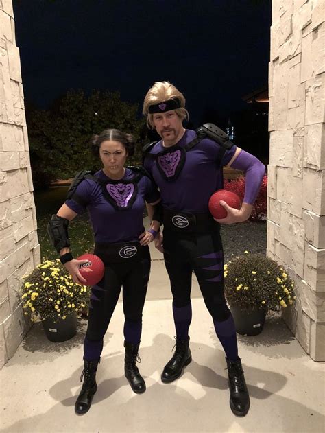 Two People Dressed In Purple And Black Holding Red Balls