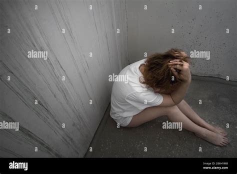 Una joven golpeada sentada sola en el piso de concreto Violencia doméstica Mujer en camiseta y